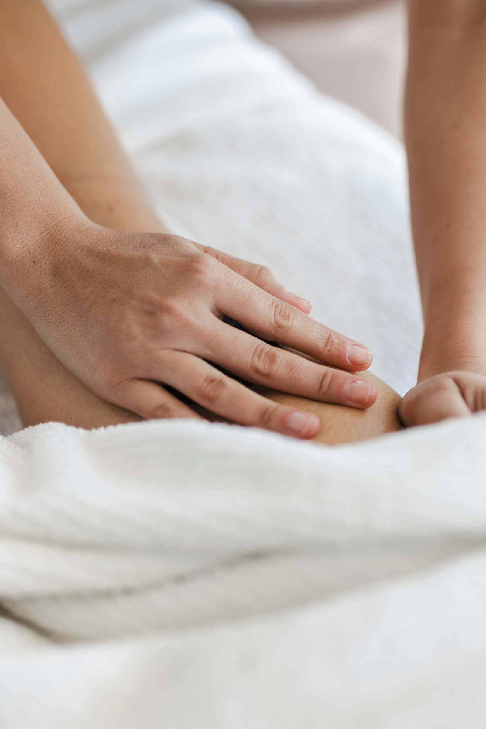 Massage therapist working on a client's leg over a white towel